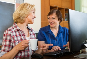 two women talking on front of monitor